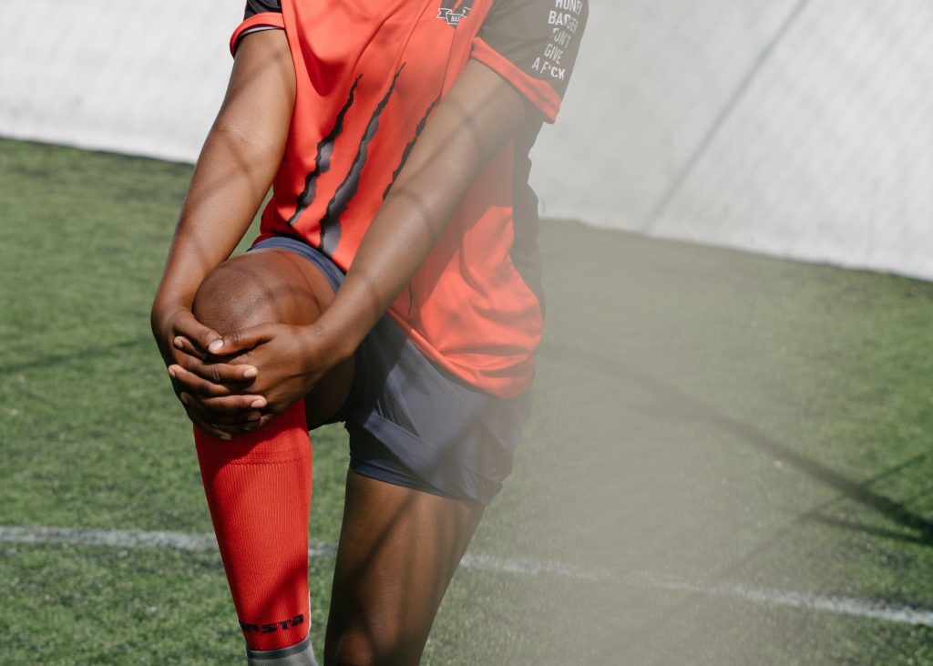 girl stretching her leg on a football pitch